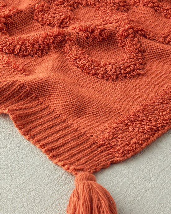 Oranje gebreide plaid met textuur, met franjes en een gedetailleerd geborduurd hartpatroon in het midden.
