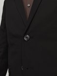 Close-up van de knoopsluiting van een zwarte JACK & JONES blazer, met een bruine blouse eronder.