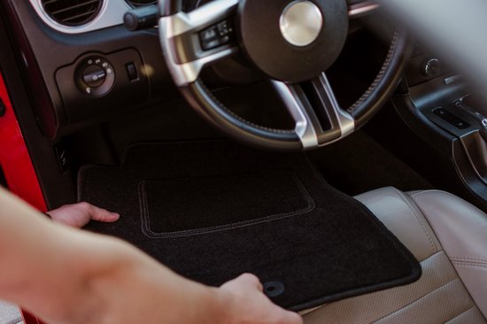 Siège de voiture en cuir gris et tapis de sol noirs dans une voiture rouge.