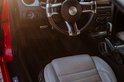 Intérieur d'une voiture rouge avec siège en cuir gris et volant noir.