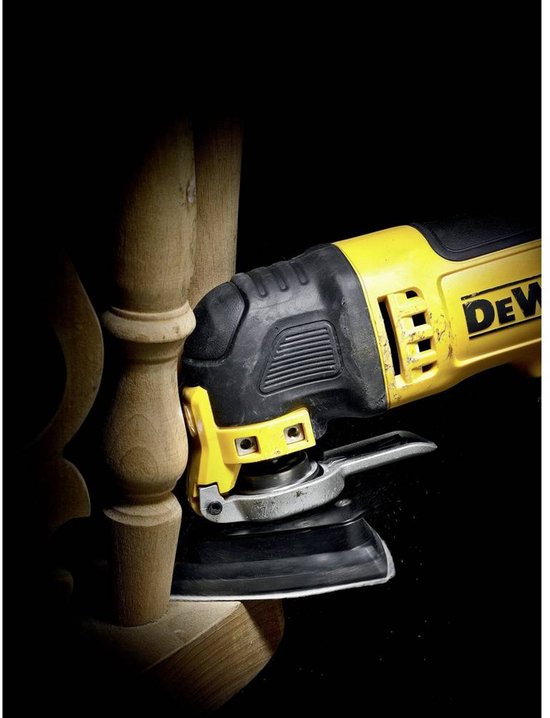 Gele DeWALT multitool schuurt een houten tafelpoot, stof dwarrelt.