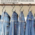 Zwarte S-haken die aan een stang hangen, met spijkerbroeken eraan.