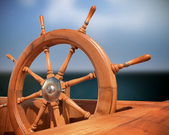 Houten scheepsstuur met een glanzende afwerking, tegen een blauwe lucht en donker water.