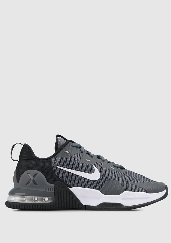 Grijze Nike Air Max Alpha Trainer 5 sneaker voor heren, zij-aanzicht. Met witte swoosh, witte zool en grijze hielkap met 'X'.