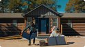 Man en vrouw zetten Jackery SolarSaga 100 zonnepanelen uit bij een houten huis, met een Jackery powerstation.