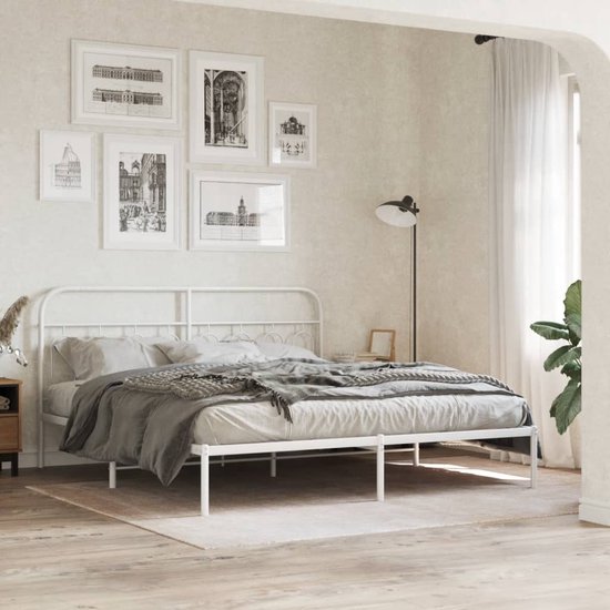 Een slaapkamer met een wit metalen hoofdbord en een opgemaakt bed met grijze dekens.