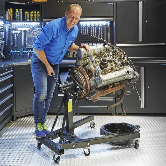 Homme en chemise bleue travaillant sur un moteur de voiture sur un support moteur.