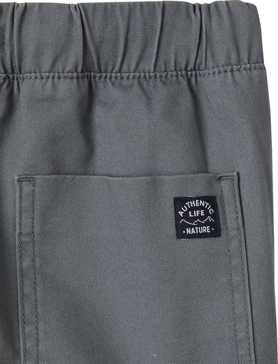 Detail van het 'Authentic Life Nature' label op de achterzak van een grijze joggingbroek.