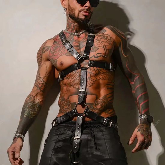 Man met zwart kunstleren harnas, tattoos, zonnebril, leren broek.
