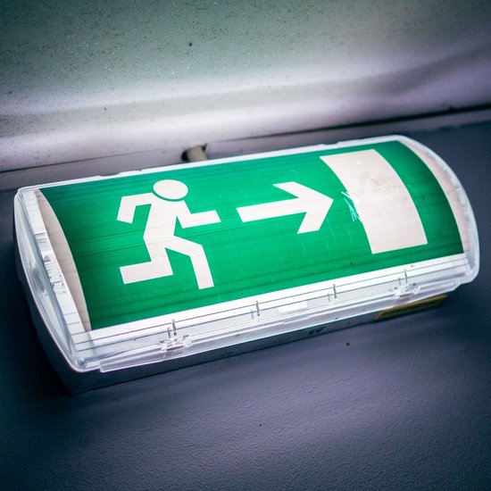 Groene nooduitgang verlichting met witte pictogram van rennend persoon met pijl naar rechts.