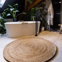 Een rond vloerkleed van natuurlijk jute met gevlochten patroon in een badkamer.