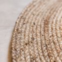 Textuur van een rond vloerkleed van gevlochten jute met zichtbare vezels.