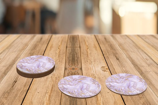Trois sous-verres ronds à motif marbre lilas et or sur une table en bois.
