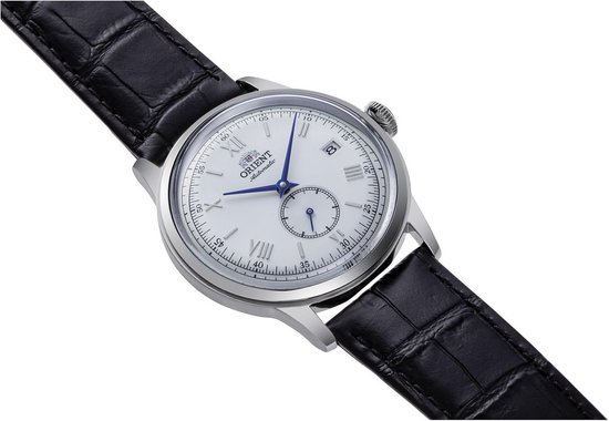 Oriënt horloge met witte wijzerplaat, blauwe wijzers, kleine secondewijzer en datum, op zwarte krokodillenleren band.