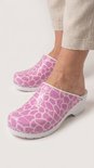 Voeten in roze klompen met wit giraffeprint, gedragen met beige broek.