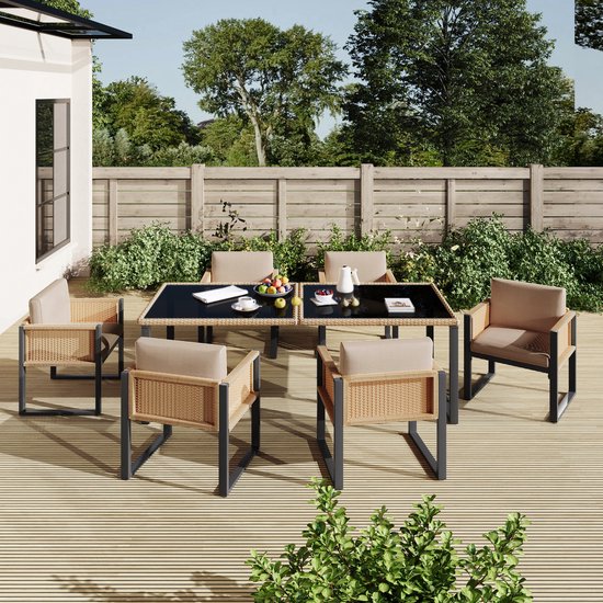 Een buiten eethoek met vier beige stoelen met rotan zijkanten en een zwart glazen tafel op een houten terras.