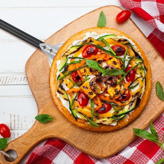 Pizza met groenten op een pizzaschep, met tomaten en basilicum.