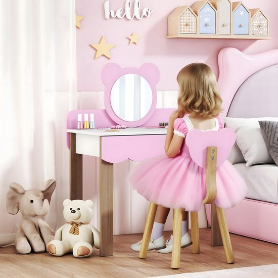 Meisje in roze jurk aan roze kaptafel met berenspiegel, speelt met make-up.
