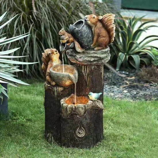 Waterfontein met eekhoorns en een vogel. Twee eekhoorns met een gieter bovenop een boomstronk, water stroomt in twee schalen. Een blauwe vogel zit op een richel.