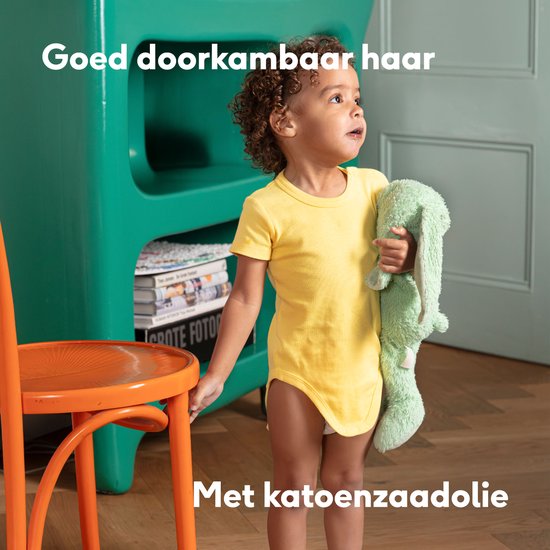 Kind met krullend bruin haar en een groene knuffel, met de tekst 'Goed doorkambaar haar met katoenzaadolie'.