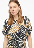 Gedetailleerde close-up van een jurk met grafische print in zwart, wit en bruin.