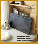 Grijze, opgevouwen Lexorion bedtafel naast een teddybeer en kussen. 'Opvouwbare poten, makkelijk mee te nemen en op te bergen'.