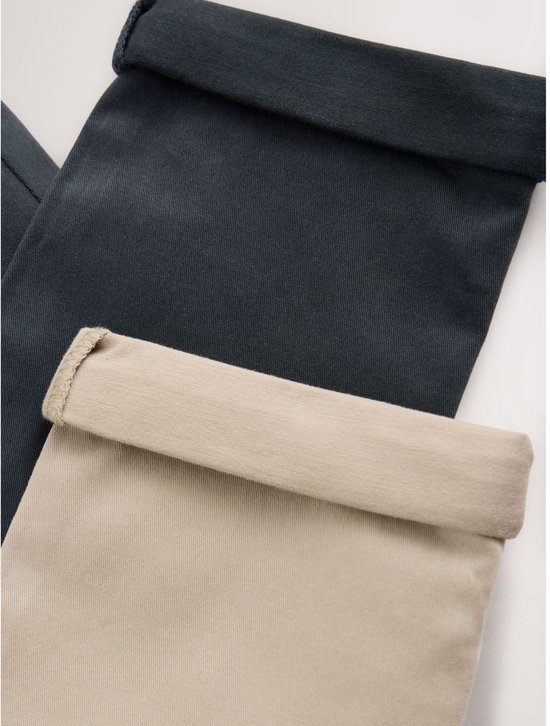 Close-up van de omgeslagen pijpen van een donkerblauwe en een beige broek.