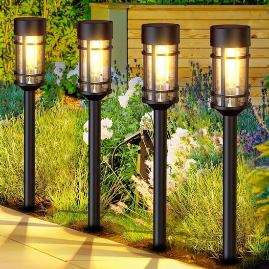Vier zwarte solar tuinlampen met vlam-effect LED verlichting in een tuin.
