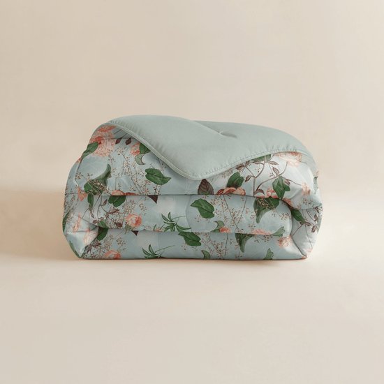 Een gevouwen lichtgroen dekbed met een print van roze en oranje bloemen en groene bladeren.