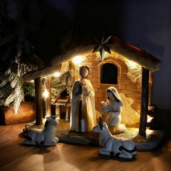 Verlichte kerststal met Jozef, Maria met baby, os en ezel, op een houten ondergrond.