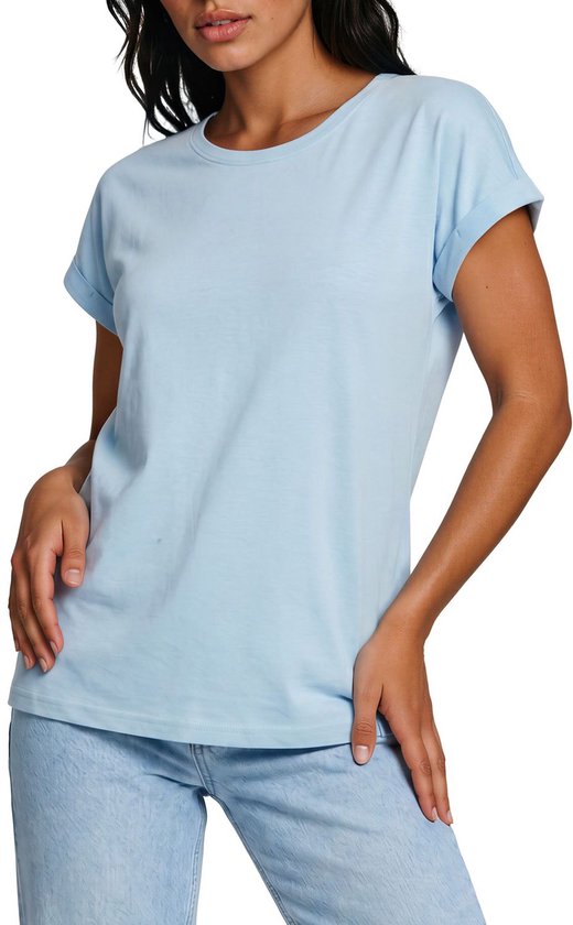 Model met lichtblauwe top met opgerolde mouwen en jeans.