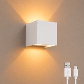 Een witte kubusvormige wandlamp die opwaarts en neerwaarts licht geeft, met twee USB-kabels.