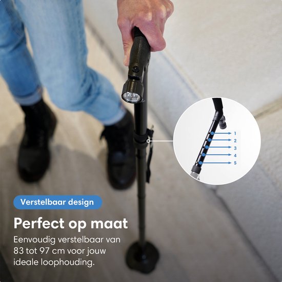 Man met blauwe jeans en zwarte schoenen die een verstelbare zwarte wandelstok vasthoudt.