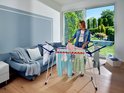 Een vrouw plaatst kleding op een wit droogrek met blauwe accenten.