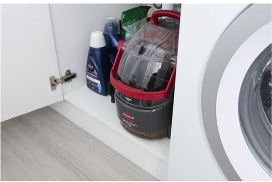 Een BISSELL SpotClean Pro op een witte plank, naast schoonmaakmiddelen.