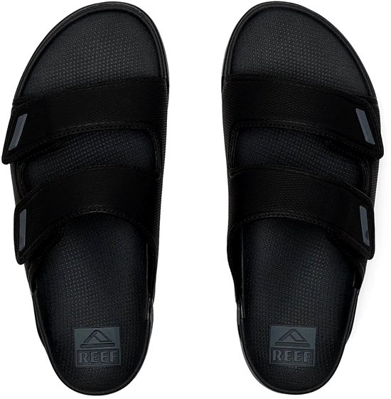 Paar zwarte synthetische slippers met twee banden en klittenbandsluiting. REEF logo op de zool.