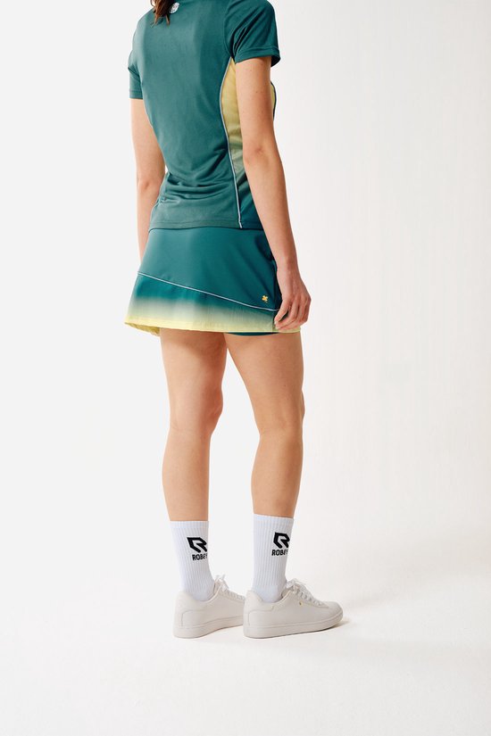 Model draagt een groen-gele sportrok met krijtstreepmotief.