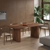 Eettafel van lichtbruin mangohout met een ovaal blad en gestreepte poten, in een eetkamer.