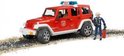 Rode brandweerauto Jeep Wrangler met brandweerman, staand op een ondergrond van zand en stenen.