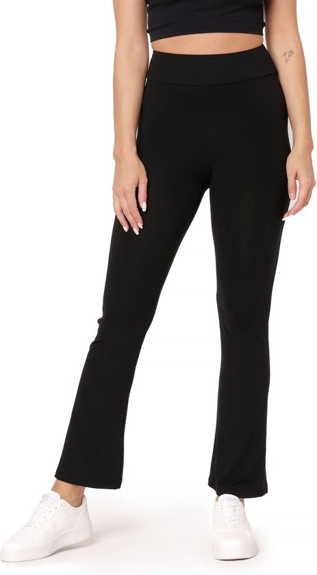 Close-up van een model in een zwarte crop top en een zwarte flared sportbroek met splitjes aan de onderkant. Ze draagt witte sneakers.