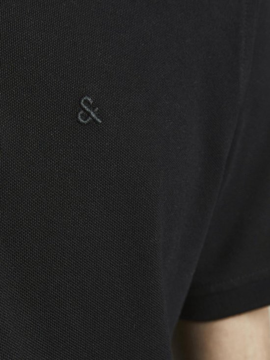 Detail van het geborduurde logo op een zwarte polo.