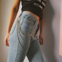 Goudkleurige pantalonketting met drie lagen schakels, gedragen aan een spijkerbroek.