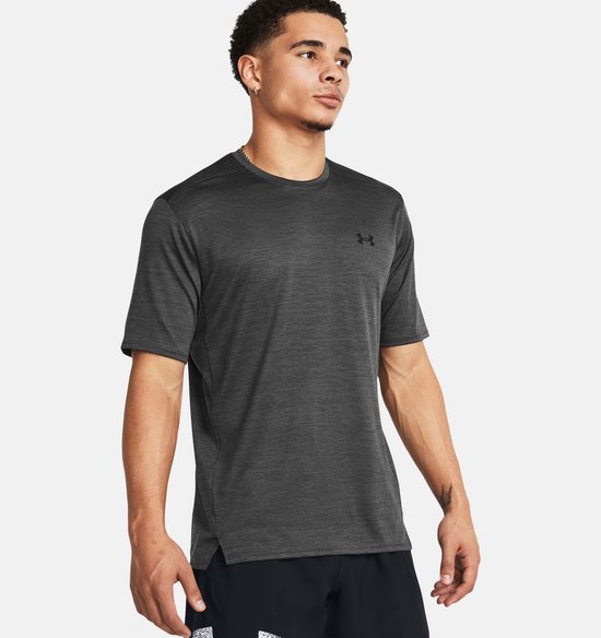 Man draagt grijs sportshirt met subtiel streepmotief en zwart Under Armour logo.