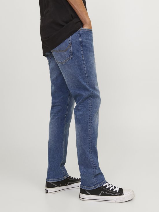 Man van de zijkant gezien, draagt een zwarte T-shirt en blauwe jeans.