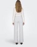 Model van achteren gezien in wijde, lichtgrijze jeans en een witte blouse.