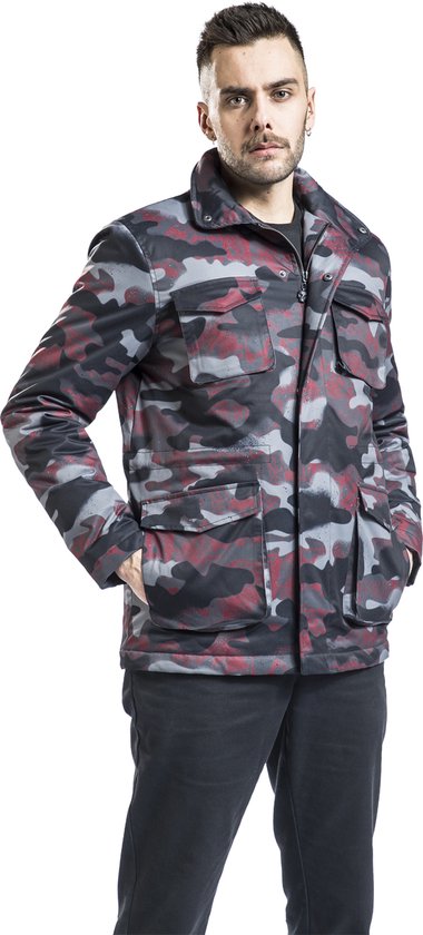 Man draagt jas met camouflageprint in grijs, zwart en rood, met vier zakken op de voorkant en opstaande kraag.