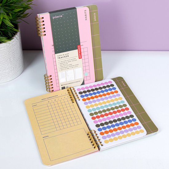 Carnet de motivation rose avec dos vert et superposition. Comprend un tracker d'habitudes, des notes et une feuille d'autocollants à pois colorés.