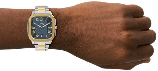 Zilverkleurig herenhorloge met gouden details op kast en schakelband. Blauw met Romeinse cijfers.