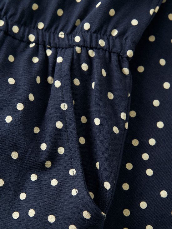 Donkerblauwe jumpsuit met beige stippen en zakken.