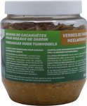 Glazen pot met vogelvoer, op de voorgrond gevuld met pindakaas en meelwormen.